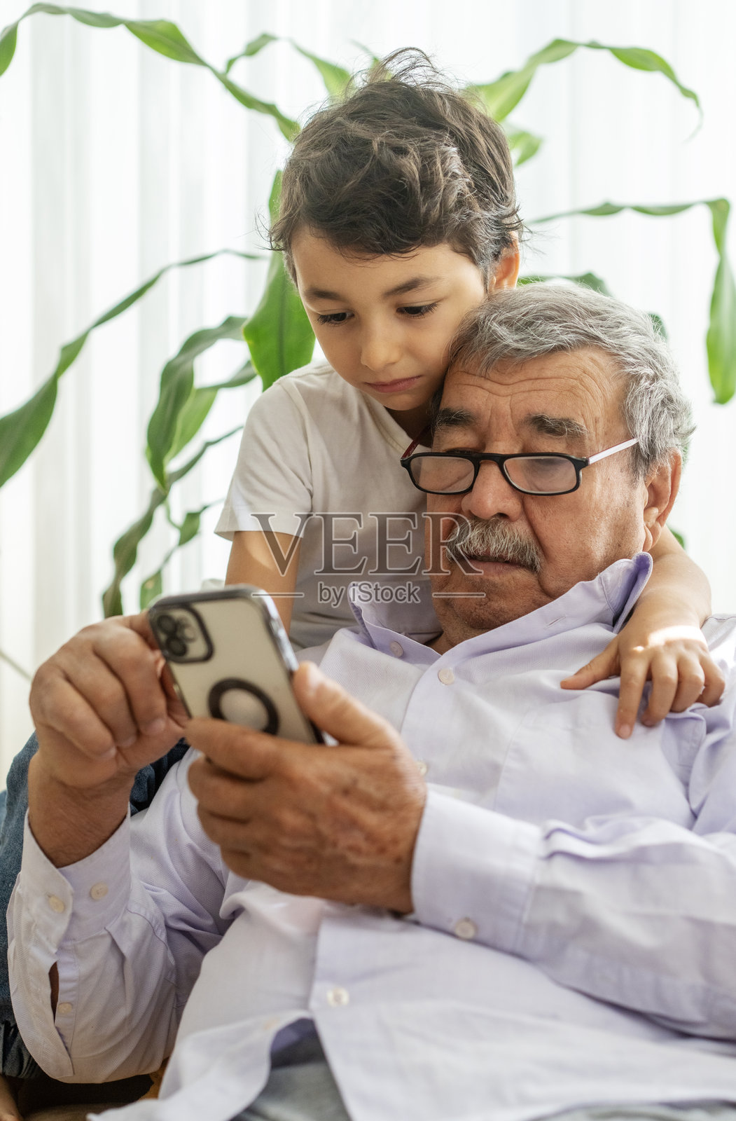 可爱的小男孩和爷爷在家一起使用智能手机照片摄影图片