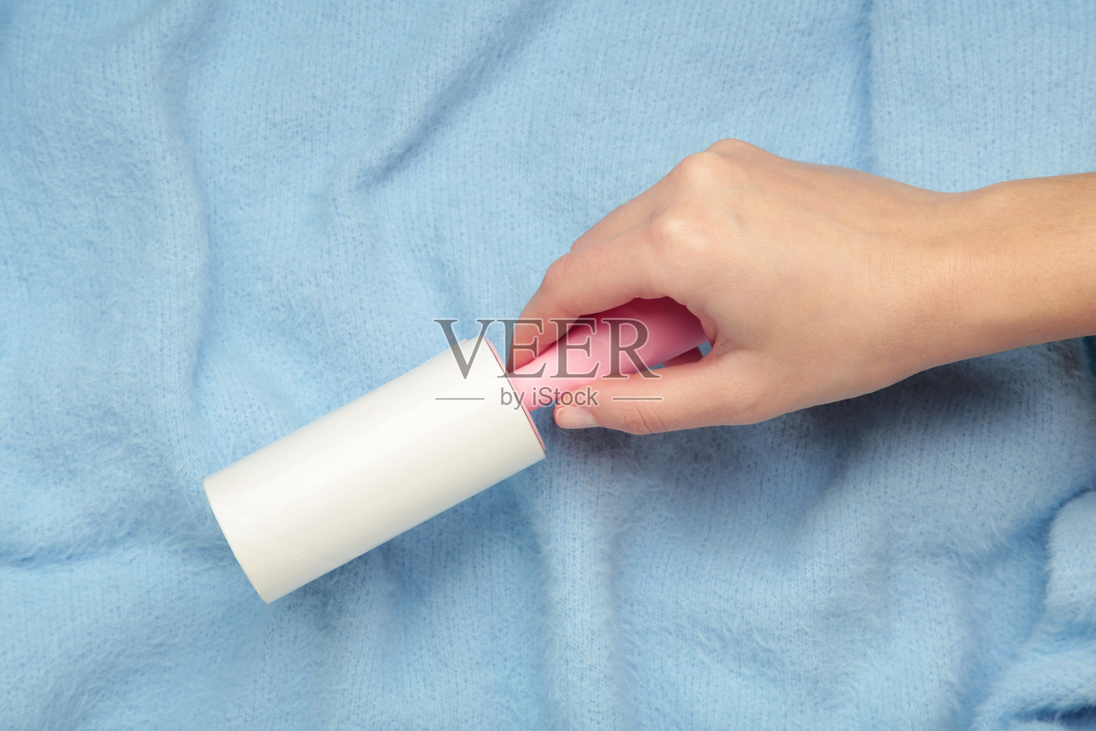 女士在蓝色衣服背景纹理上清洁。粘毛滚筒，宠物猫狗毛发灰尘去除器照片摄影图片