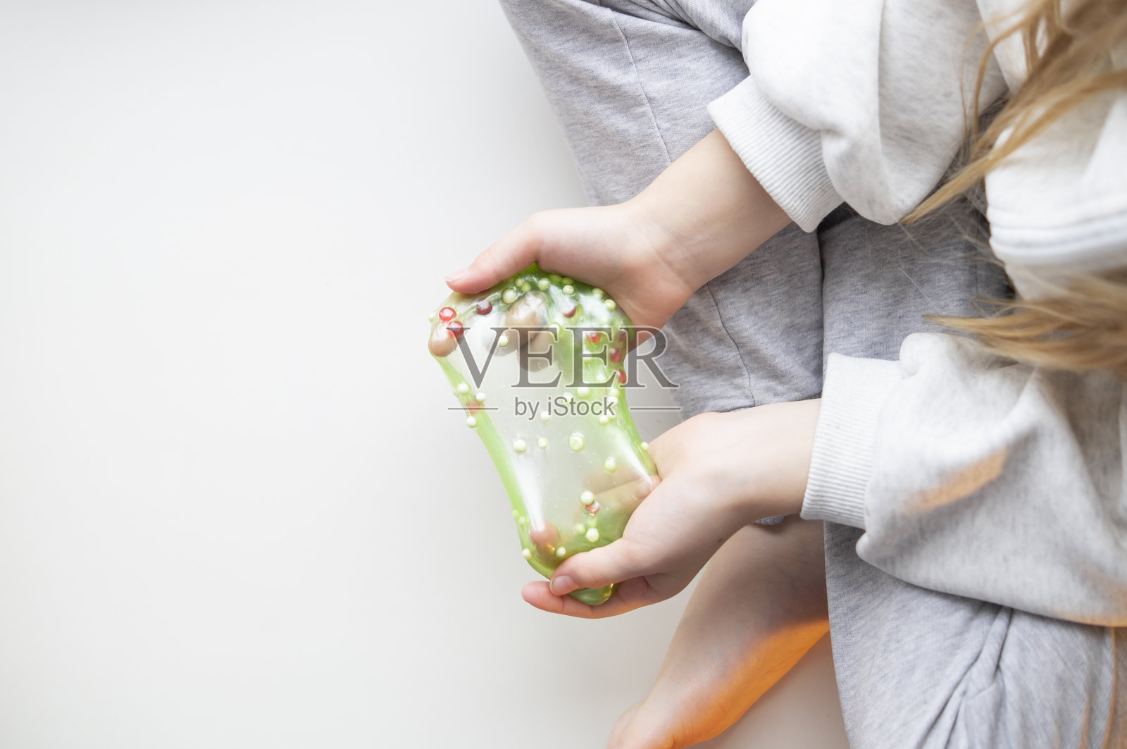 一个孩子玩着史莱姆，拉伸、挤压并探索其质感。照片摄影图片