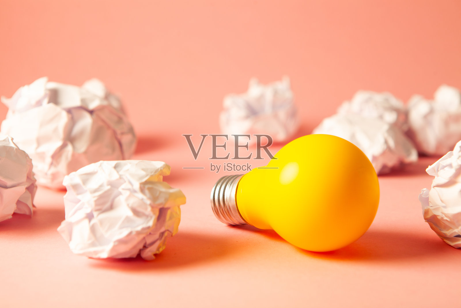 黄色背景上的纸团和揉皱的灯泡。创意想法和创造力概念。照片摄影图片