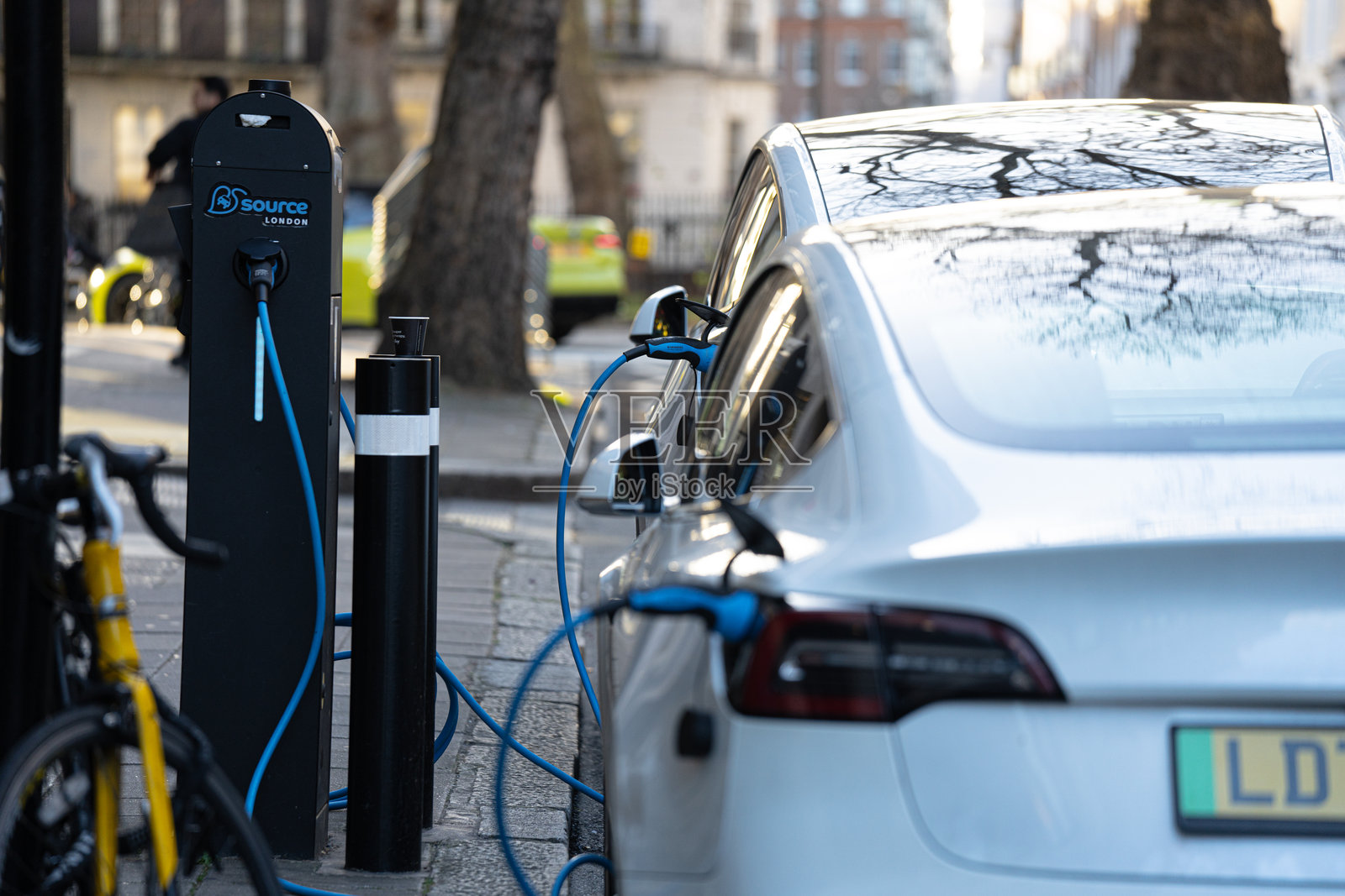 特斯拉电动汽车插入路边充电桩，充电单元，电动汽车后视图，伦敦市中心照片摄影图片