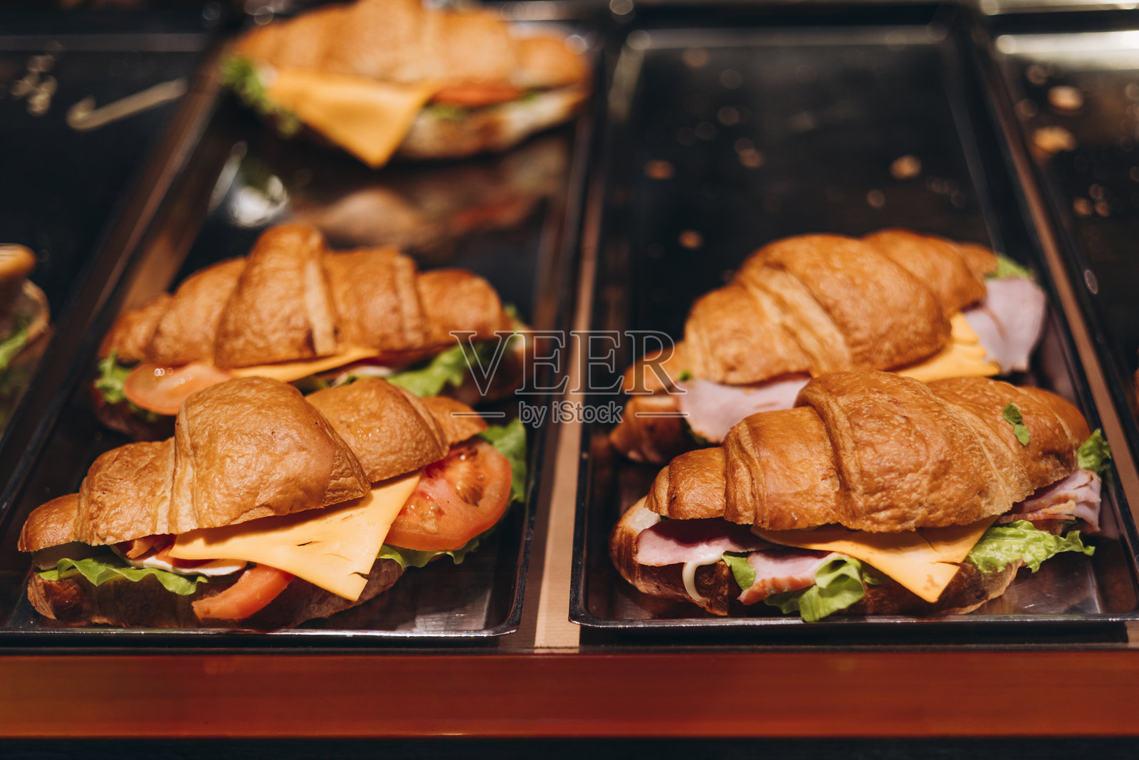 咖啡馆展示柜里的美味可颂，内含火腿、奶酪和蔬菜，俯视角度。照片摄影图片