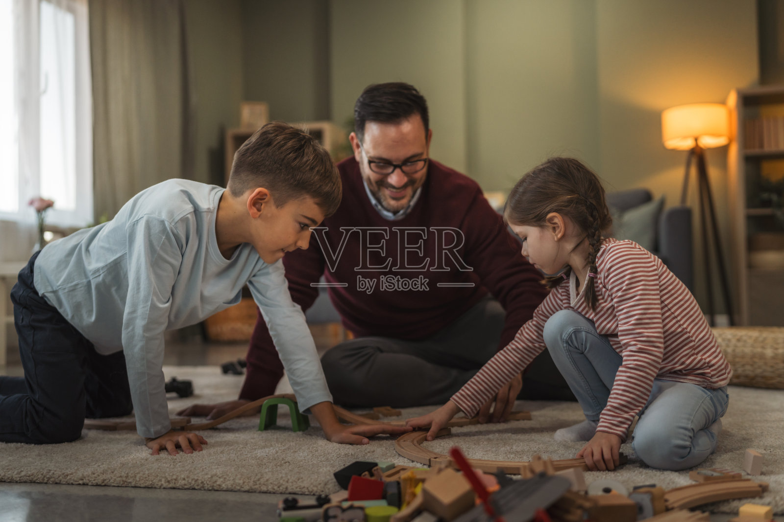 父亲和孩子们在地板上玩木制火车玩具照片摄影图片