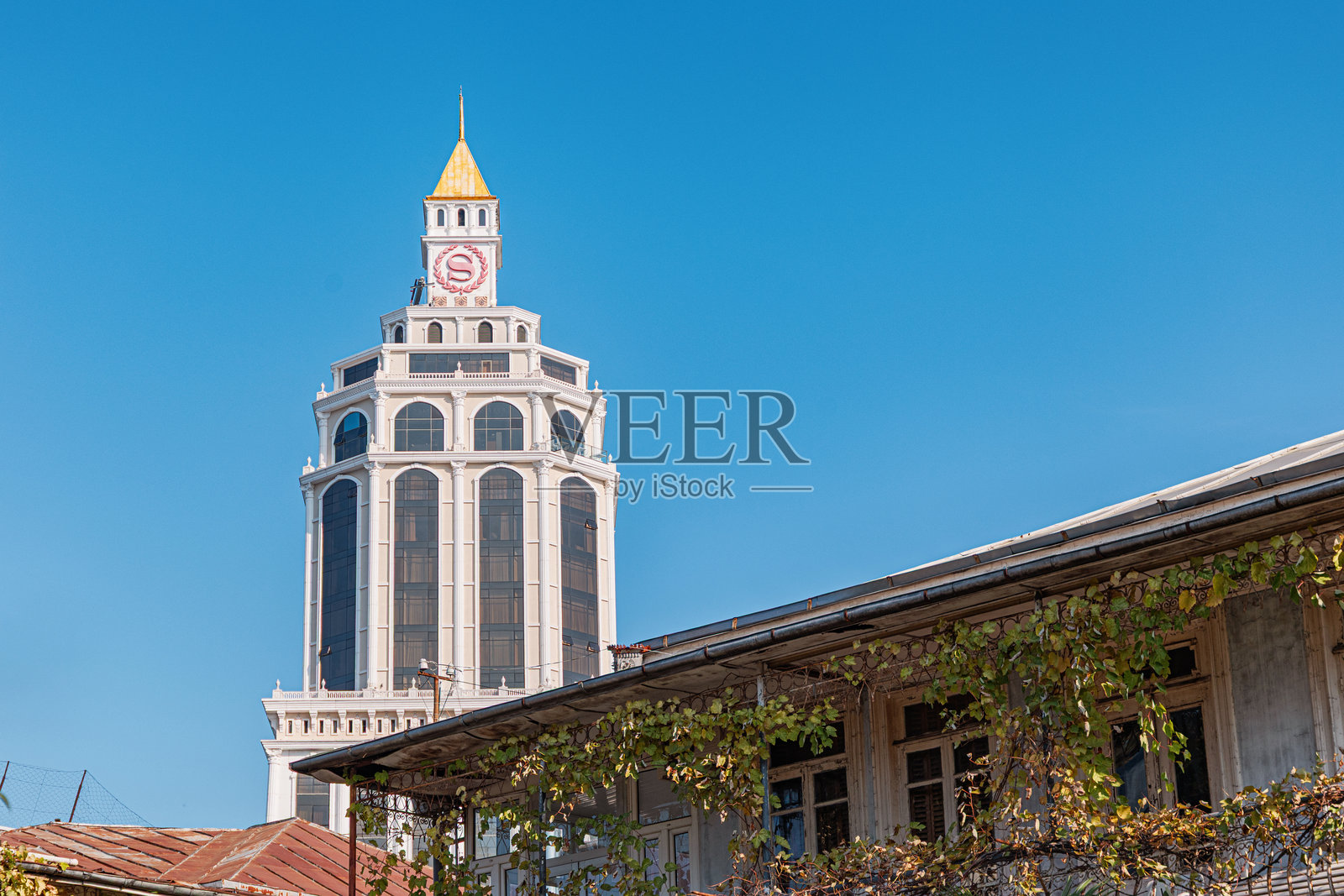 对比鲜明的建筑，现代喜来登酒店大楼矗立在爬满藤蔓的传统建筑后面照片摄影图片