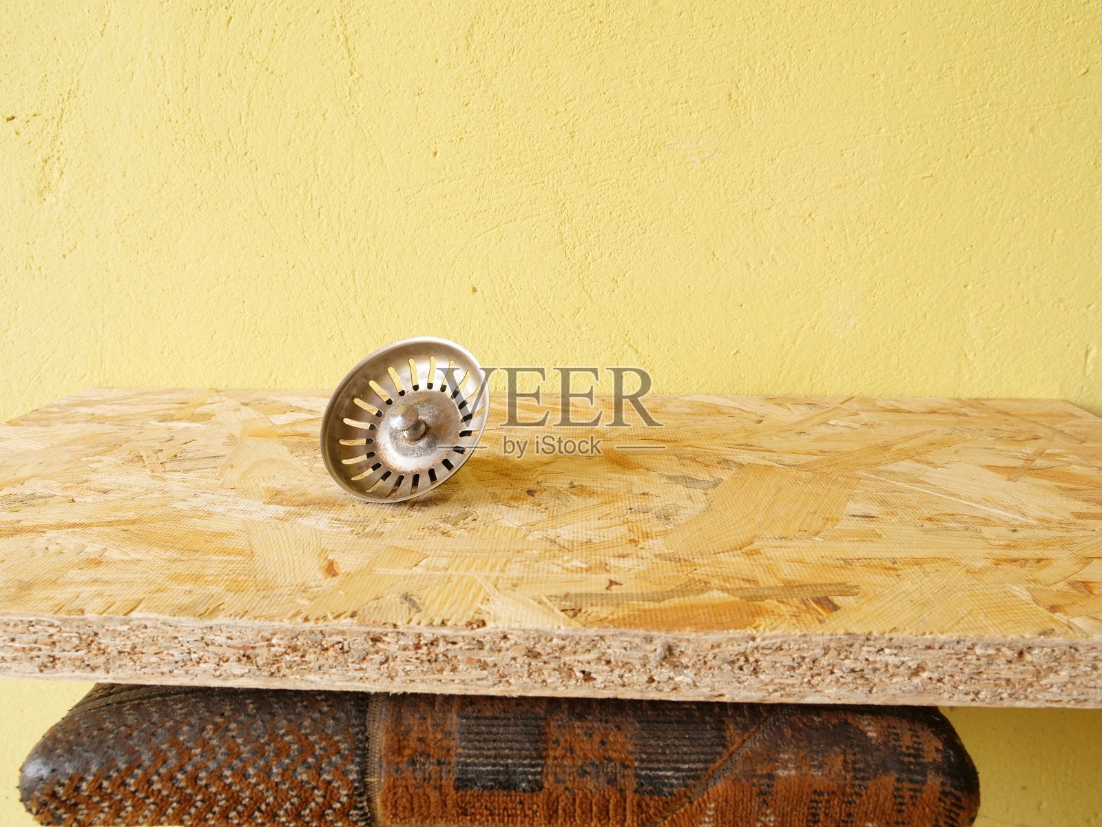 金属水槽滤水器放在木板上，背景为黄色纹理照片摄影图片