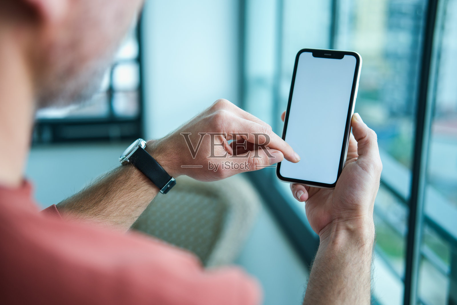 一名男子在室内使用手机。照片摄影图片