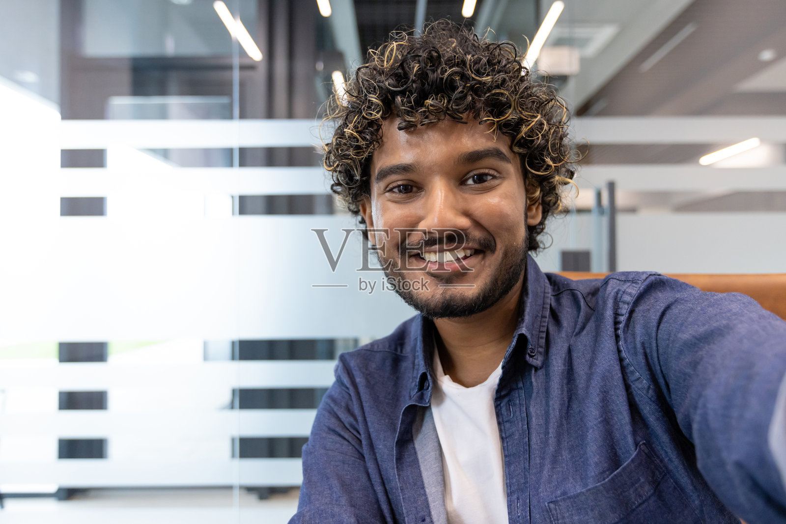 一位年轻的印度男子在办公室，近距离拍摄，他正对着镜头说话照片摄影图片