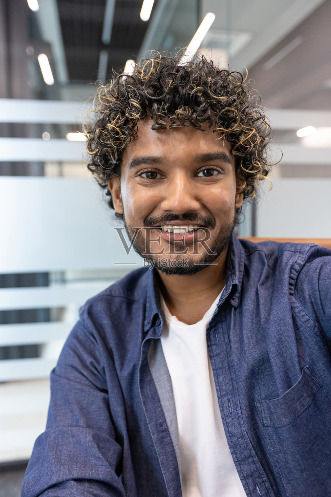 室内垂直特写照片，一名印度男子正对着手中持有的相机说话照片摄影图片