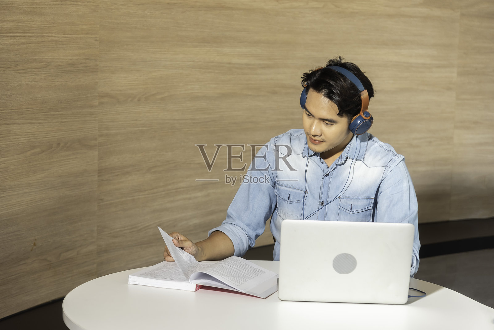 一位戴着耳机的快乐亚洲呼叫中心客服人员，在客户支持办公室与客户交谈。照片摄影图片