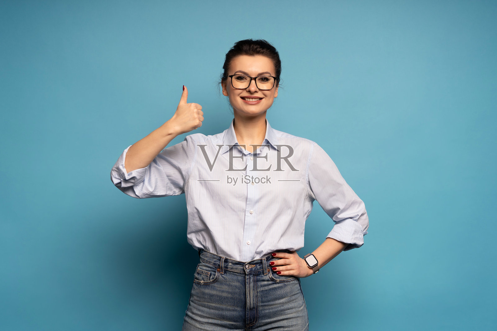 背景为蓝色的竖起大拇指的积极女性肖像。照片摄影图片
