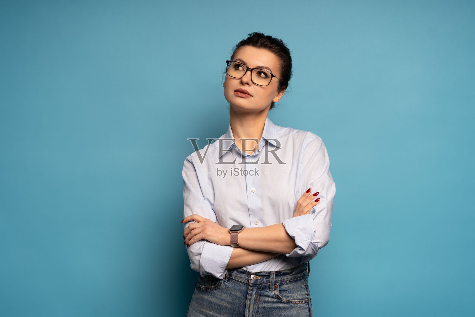 一位成功的职业女性，若有所思，独自一人在蓝色背景前照片摄影图片