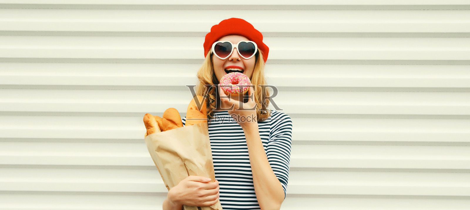 快乐开朗的年轻女子，面带微笑，手持装着法式长棍面包的购物纸袋照片摄影图片