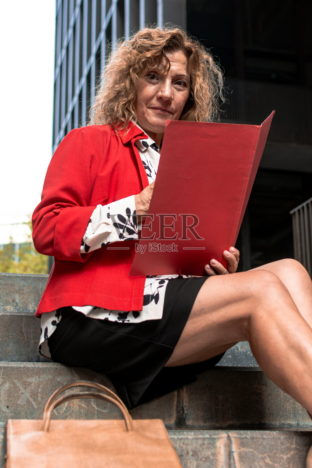 一位职业女性坐在办公楼的楼梯上审阅文件照片摄影图片