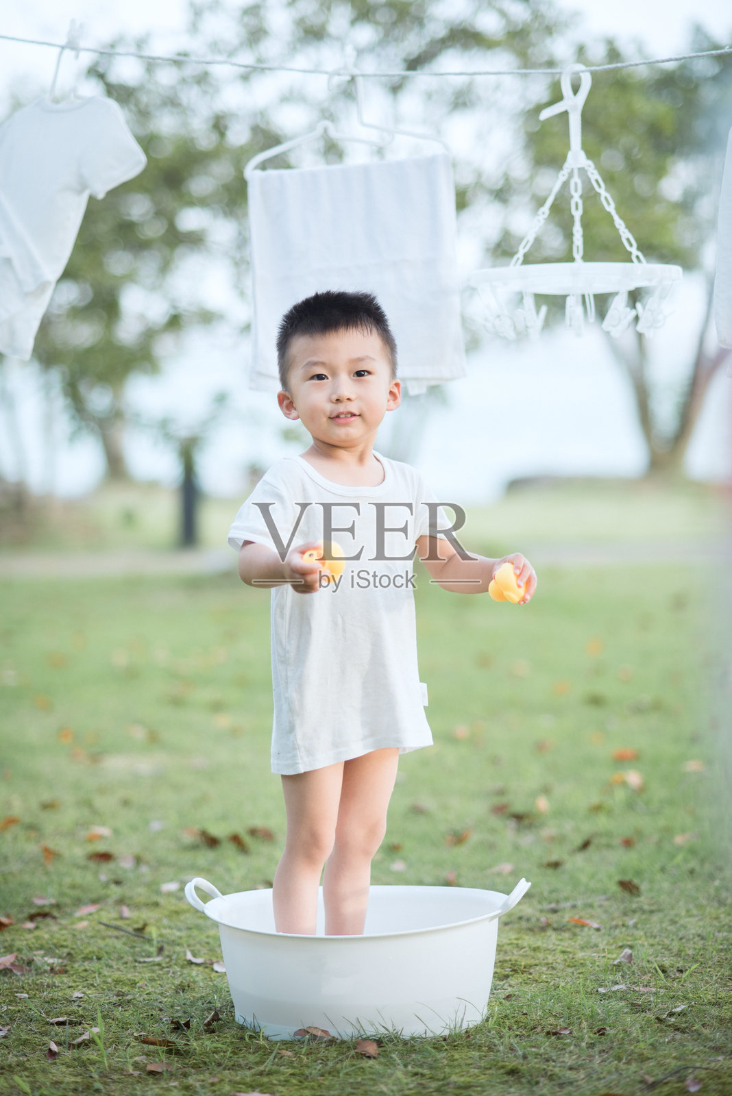 小男孩在户外洗脸盆里玩耍照片摄影图片