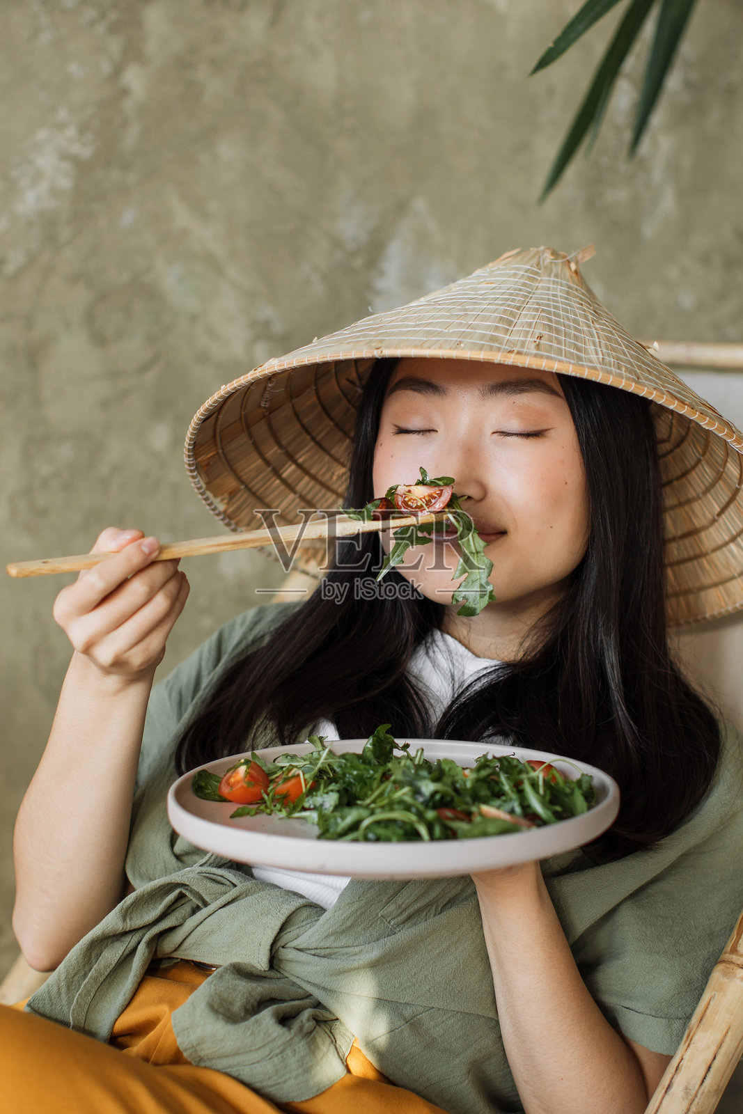 戴着亚洲帽子的女人在吃沙拉照片摄影图片