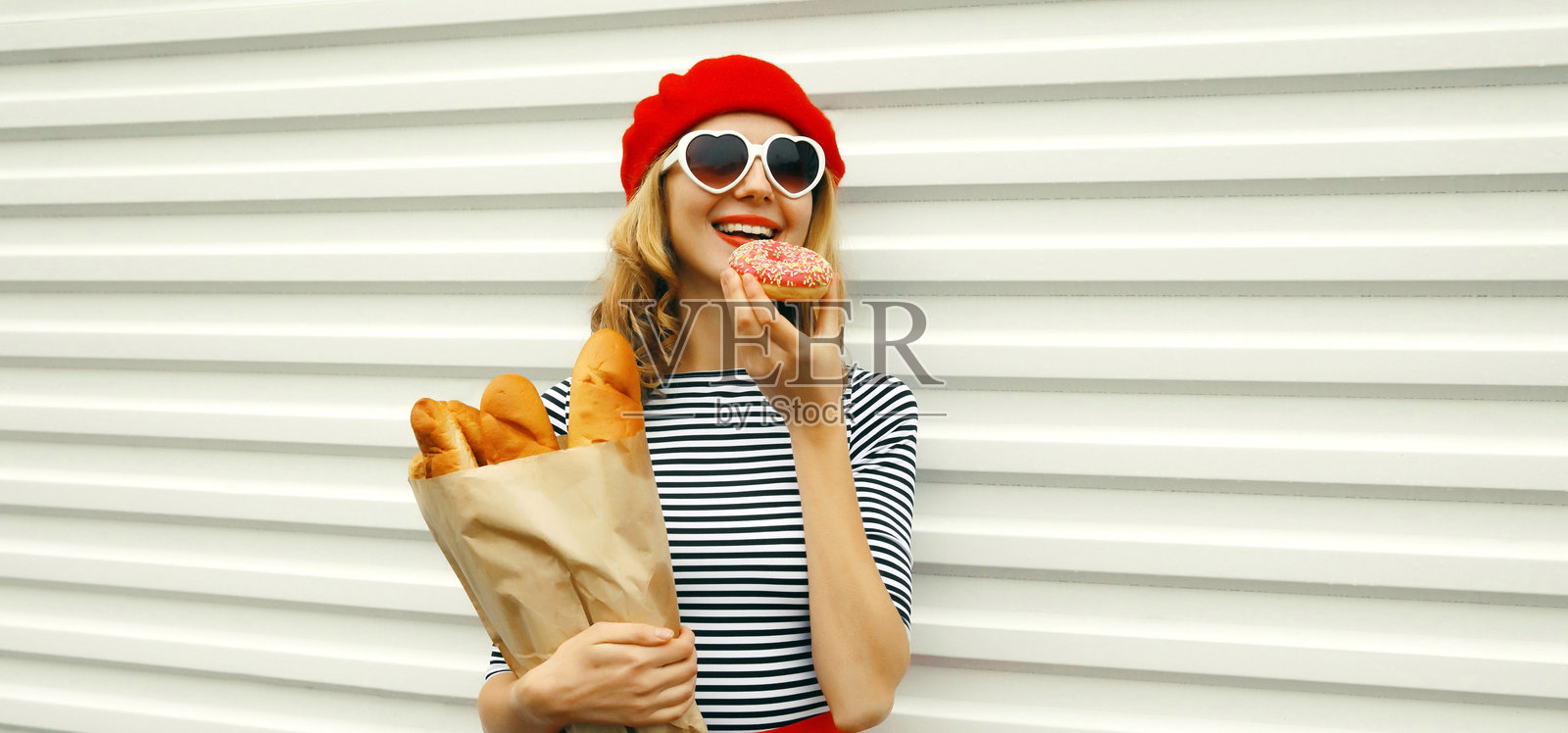 快乐、开朗、微笑的年轻女子，手持装有法式白面包的购物纸袋照片摄影图片