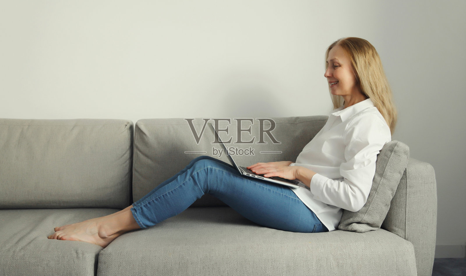 快乐的现代女性在客厅沙发上用笔记本电脑工作，自由职业者照片摄影图片