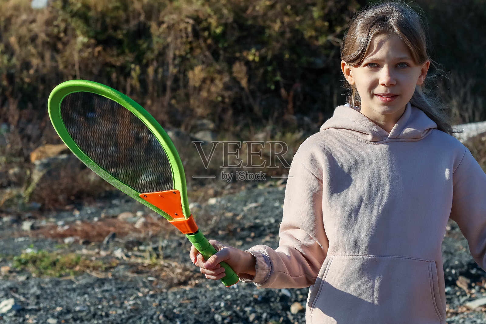 年轻女孩在户外拿着绿色网球拍照片摄影图片