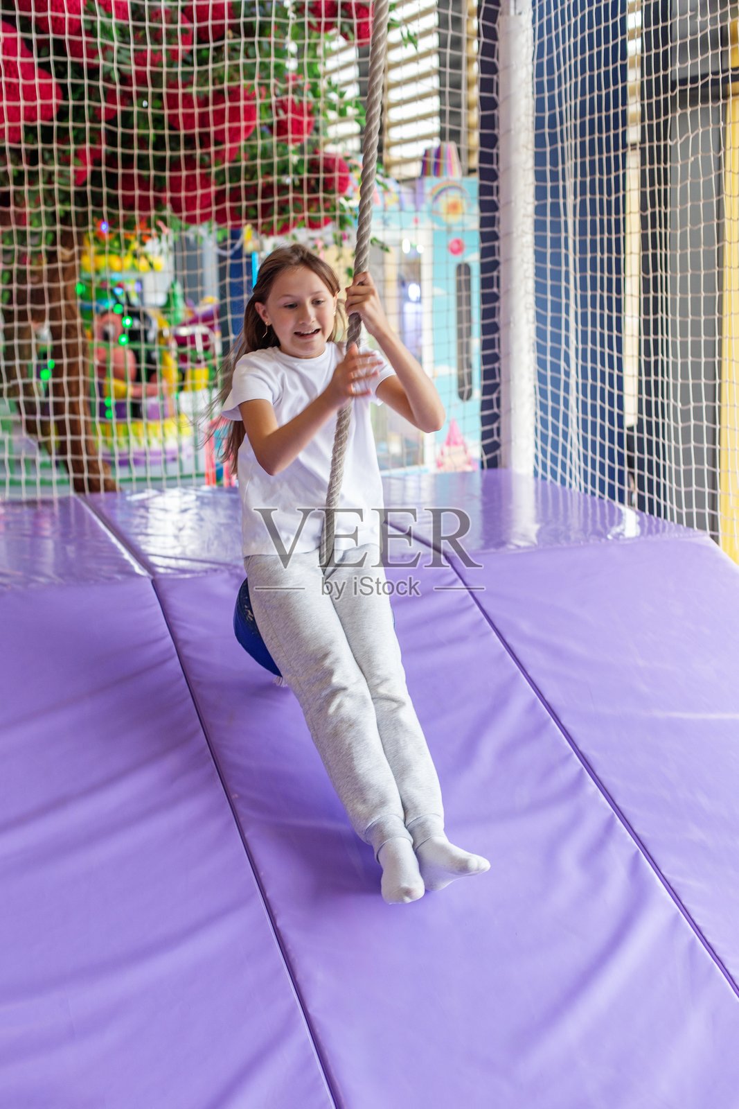 在室内游乐中心，一个少女在玩秋千照片摄影图片
