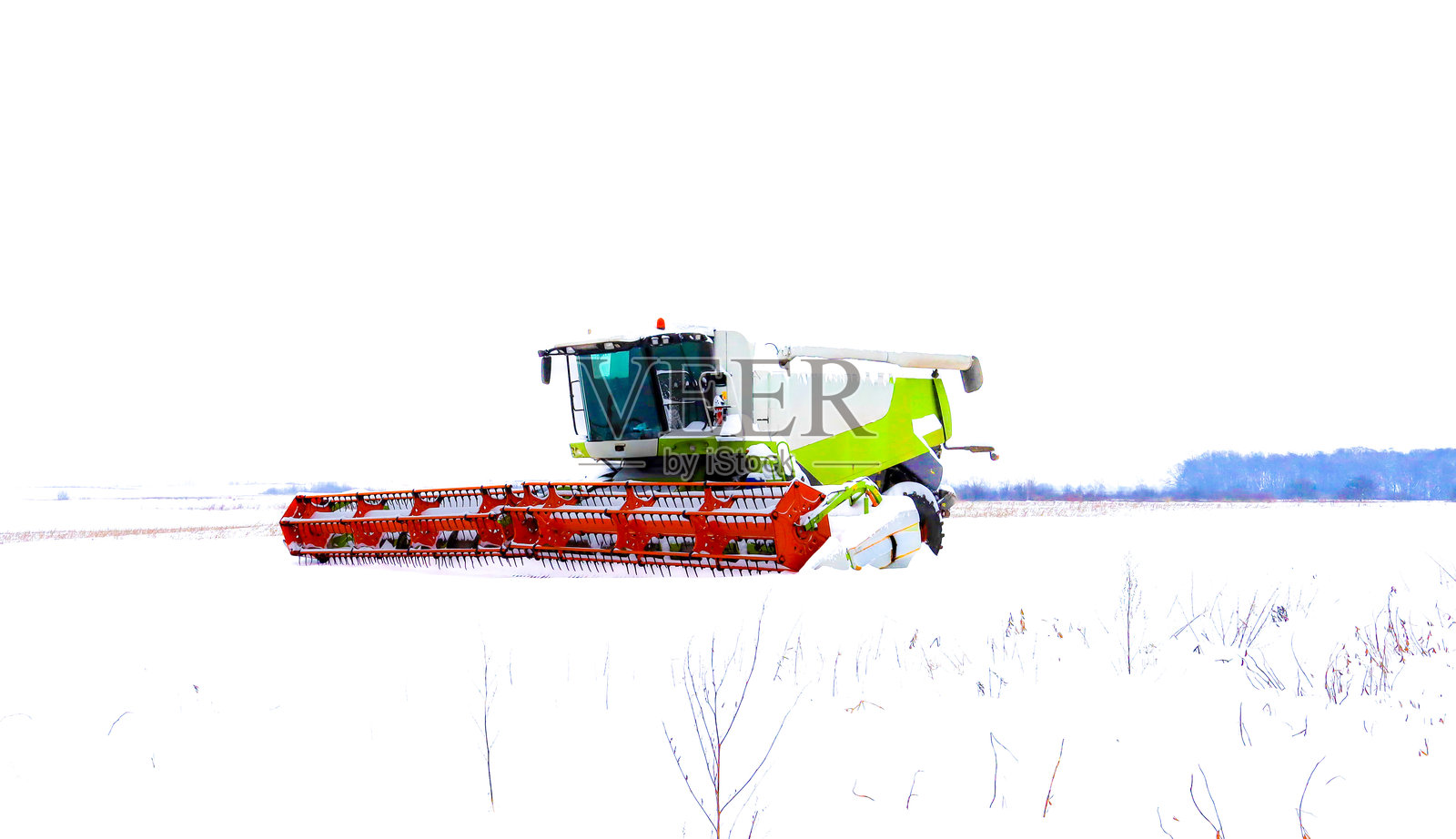 冬季休耕期在开阔田野中的现代化谷物收割机。这台强大的农业机械配有明亮的割台，部分覆盖着积雪，象征着其技术耐力和为即将到来的收获季节做准备。照片摄影图片