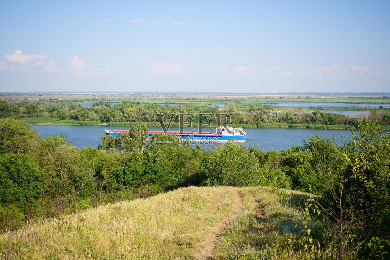 一艘驳船正在顿河上航行，周围是绿树成荫的自然风光。照片摄影图片