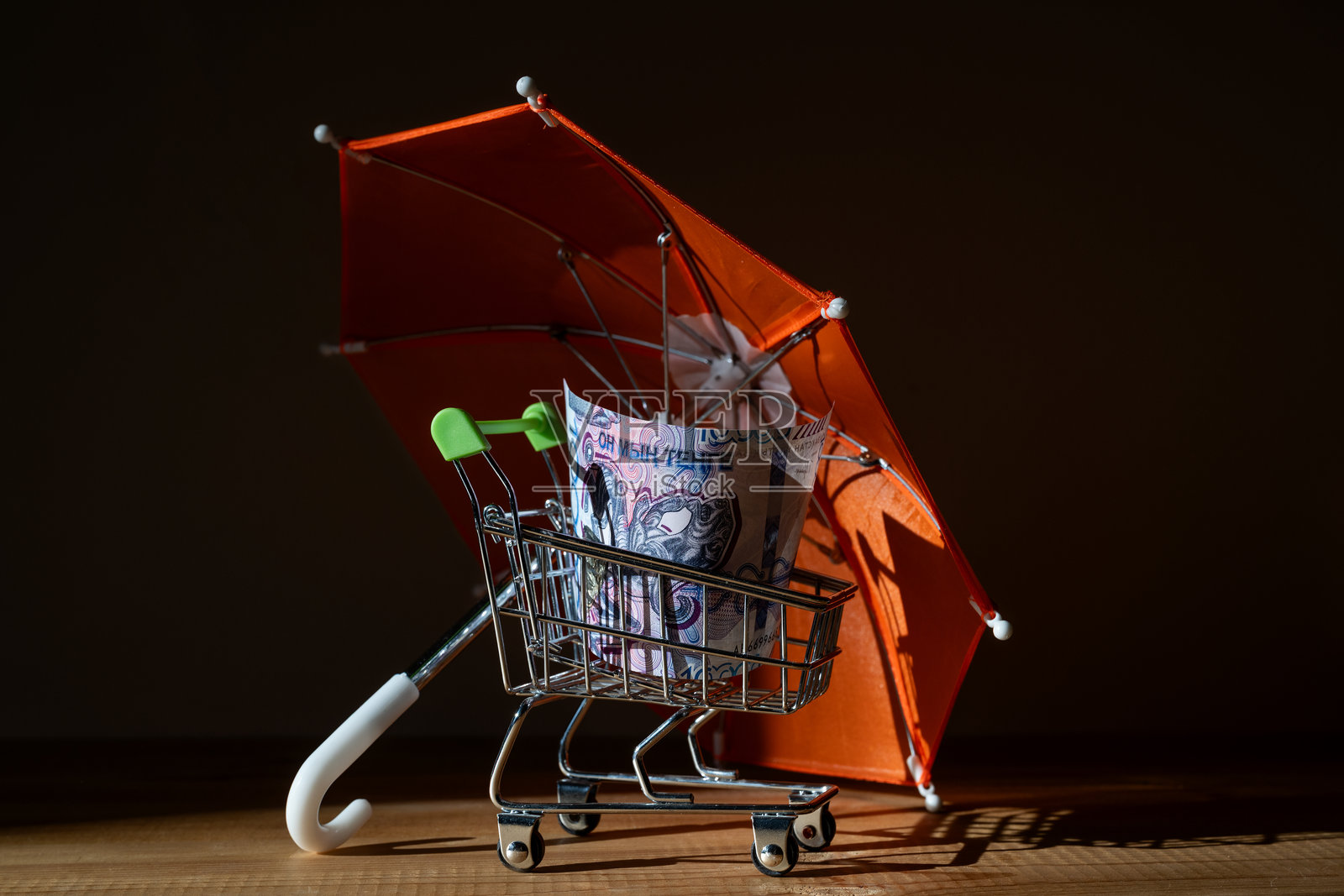 红色雨伞下，一辆迷你购物车里装着一千哈萨克斯坦坚戈纸币照片摄影图片