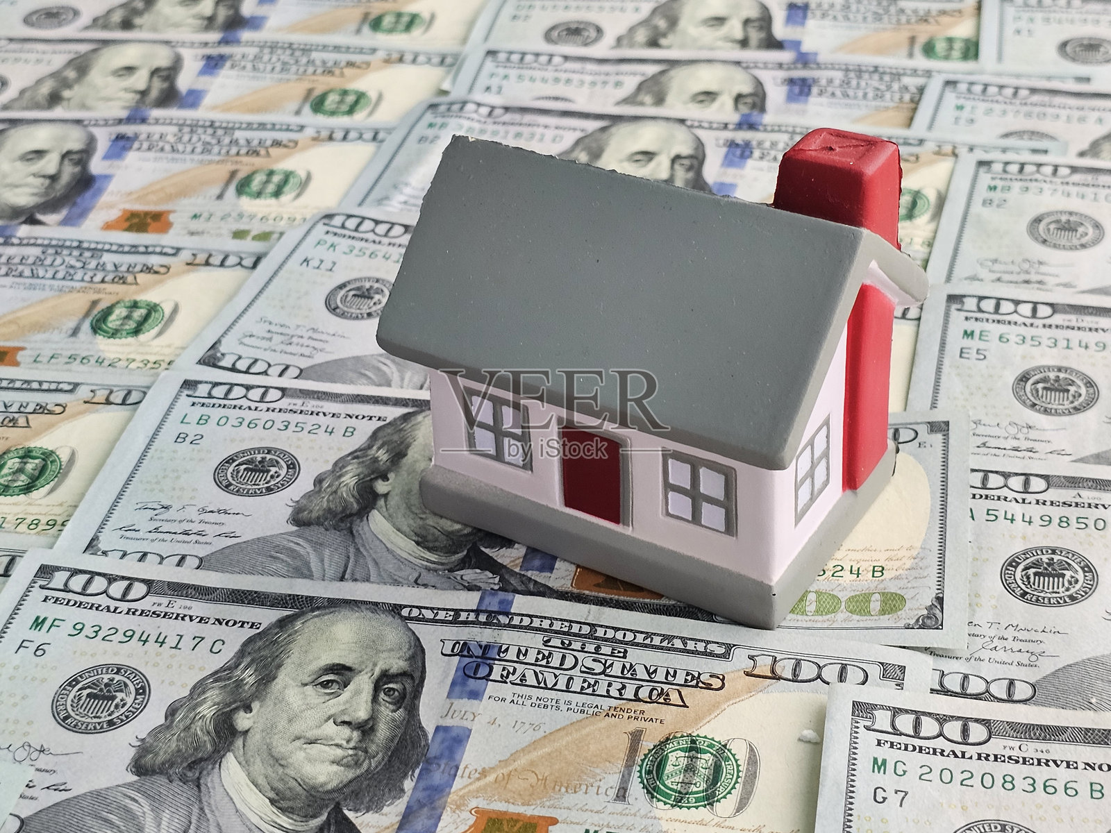房屋坐落在百元美钞之上，象征着房地产市场和投资机会的概念照片摄影图片
