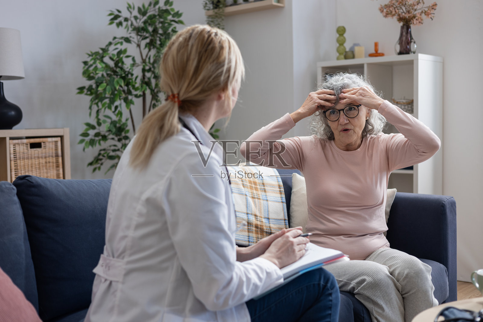 护士在家拜访一位头痛的老年女性照片摄影图片