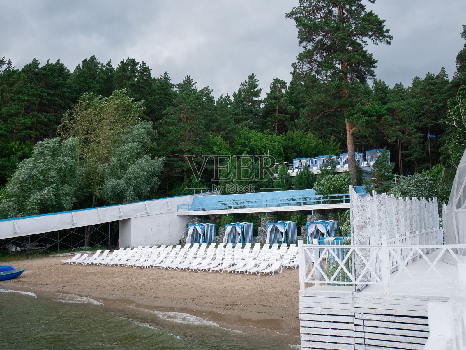 空旷的海滩，配有躺椅，靠近绿色森林和湖岸。夏季度假和旅行背景的休闲区。照片摄影图片