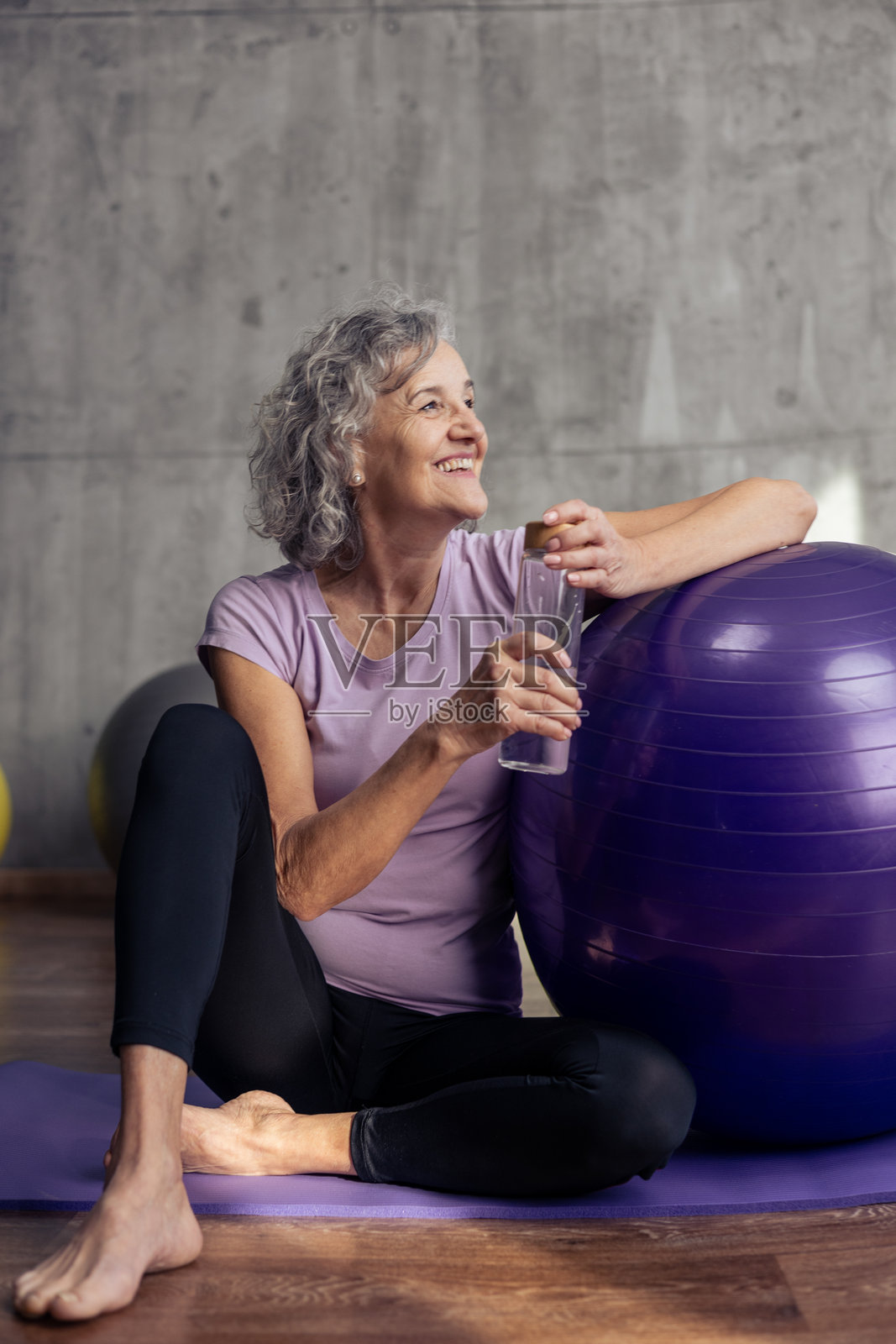 健身运动后，一位年长的女士面带微笑地喝水。照片摄影图片