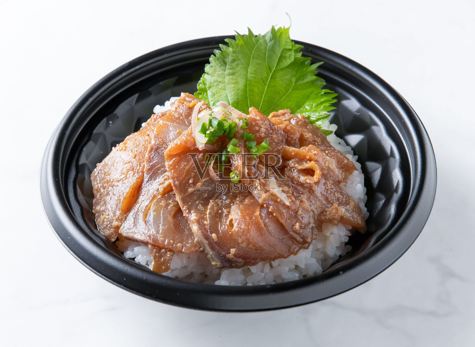 黑碗中放着米饭，米饭上铺着腌制的鰤鱼或美味的烤鳗鱼，孤立在白色背景上照片摄影图片