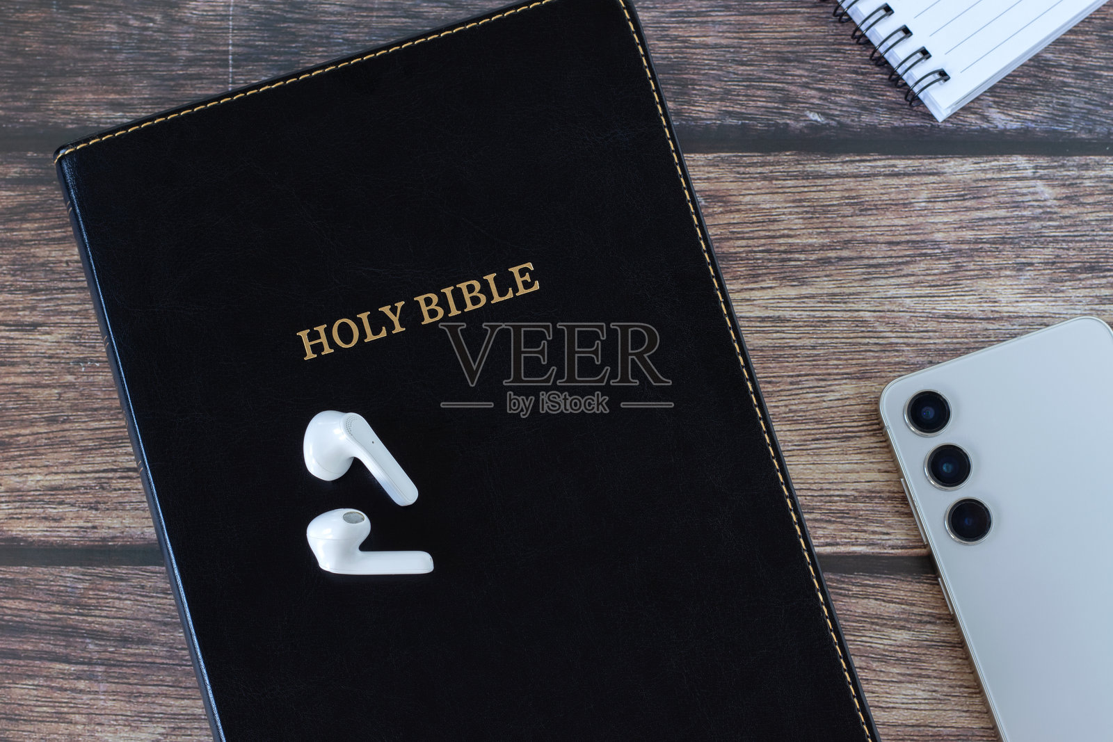 木质背景上的圣经书、耳机、手机和笔记本照片摄影图片