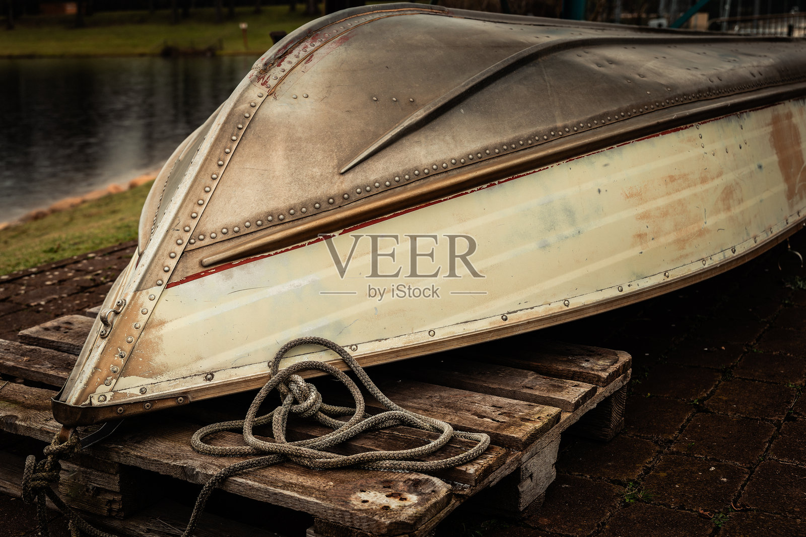 夕阳下，一艘美丽的复古船停靠在木托盘上，旁边是宁静的湖泊，天空布满云彩。照片摄影图片