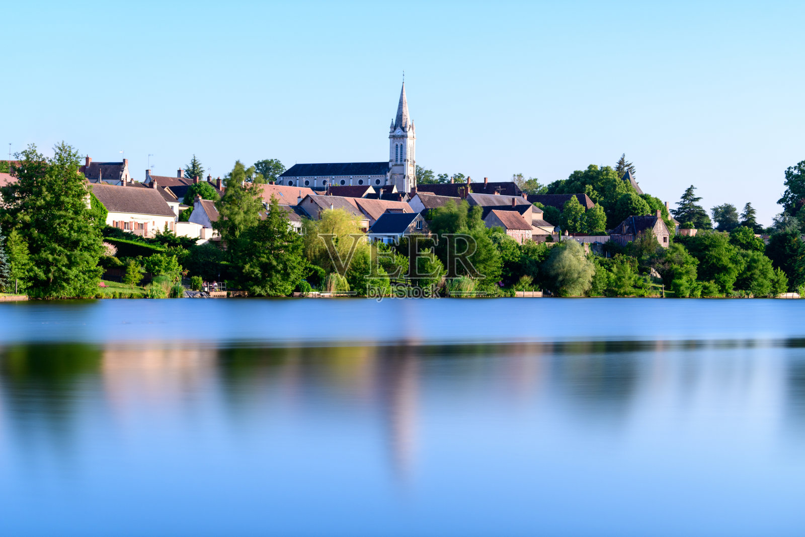 宁静的蓝色湖泊上方的村庄天际线和教堂照片摄影图片