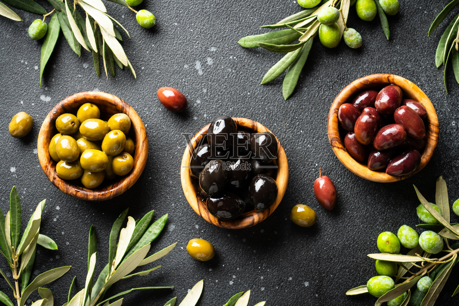 橄榄盛放在橄榄碗中，配有新鲜的橄榄枝。黑色桌面俯视视角。照片摄影图片