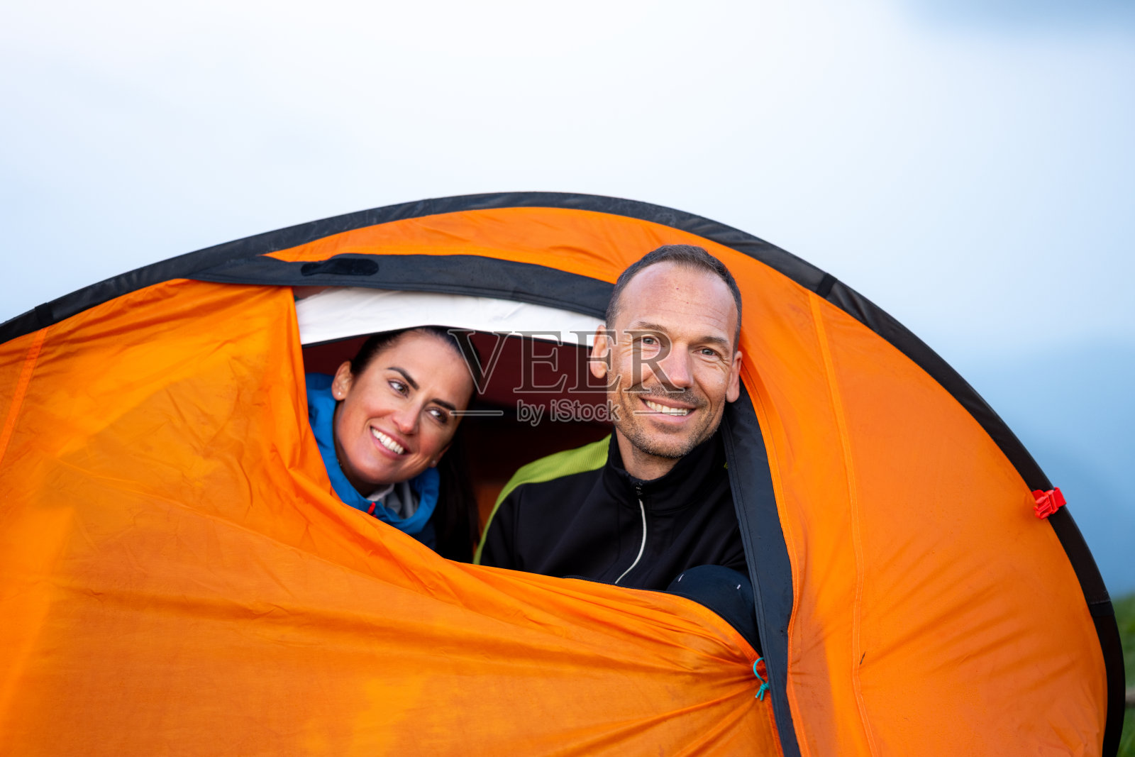 快乐的中年白人夫妇在山丘的帐篷里放松照片摄影图片