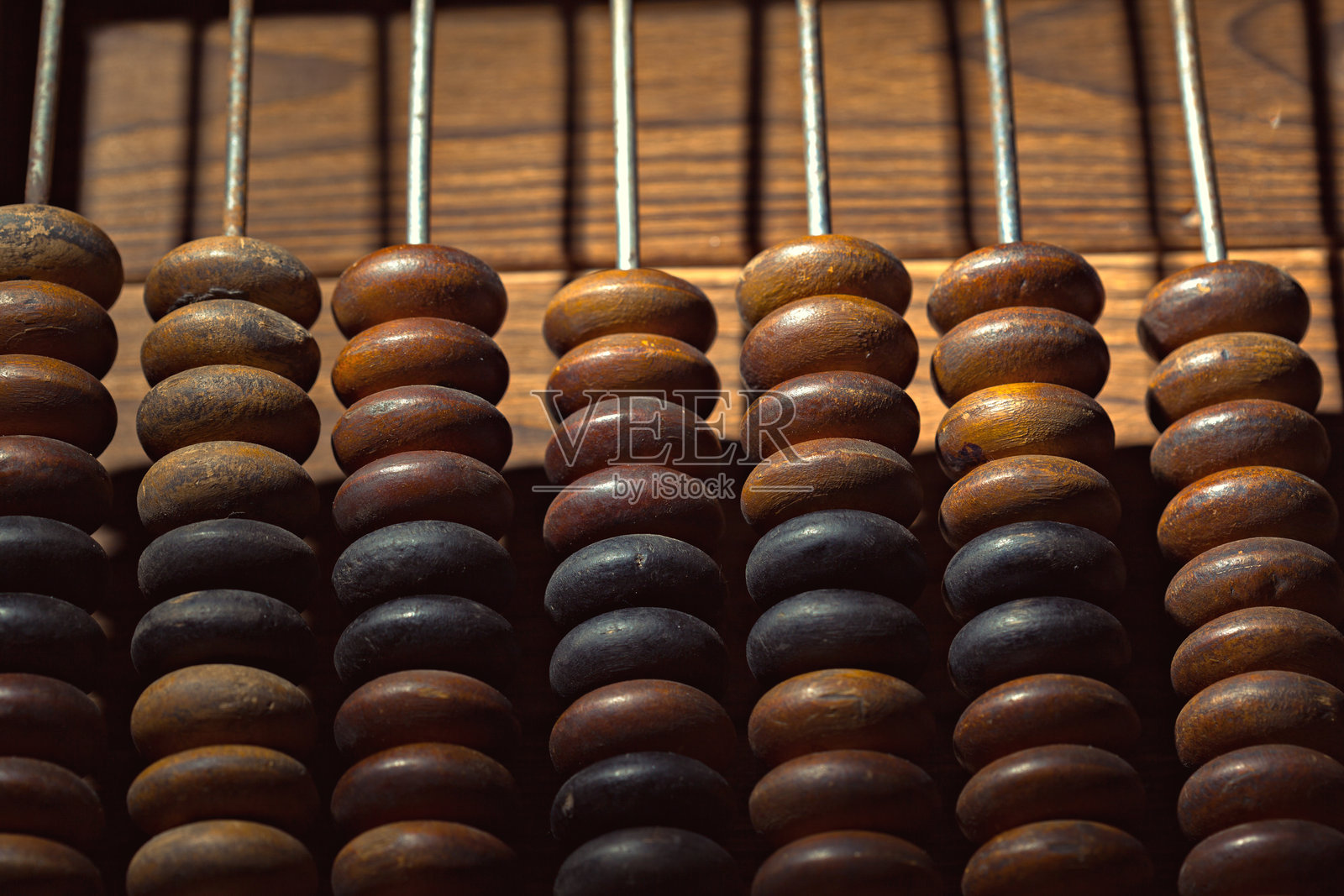 木制算盘，珠子有深浅两种颜色，排成一列放在木制表面上照片摄影图片