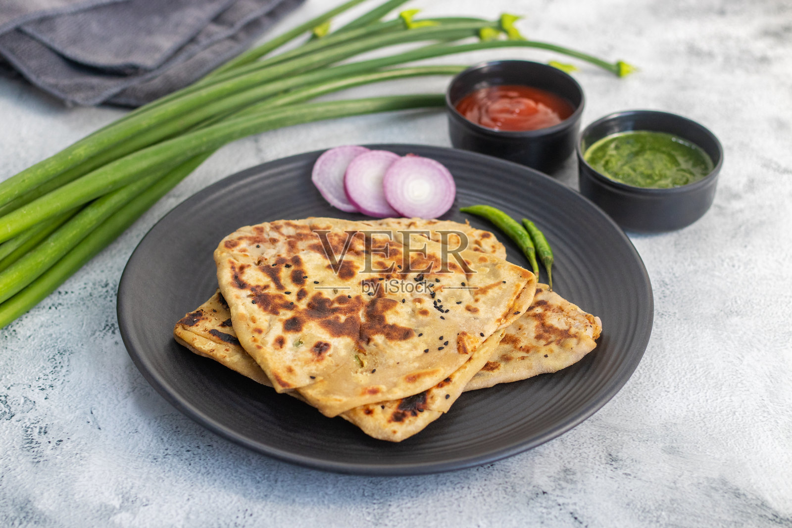 金黄洋葱葱油饼，内馅为焦糖洋葱、香料和香草，香煎至酥脆，内里松软，香气浓郁，是暖心又传统的印度早餐薄饼。照片摄影图片