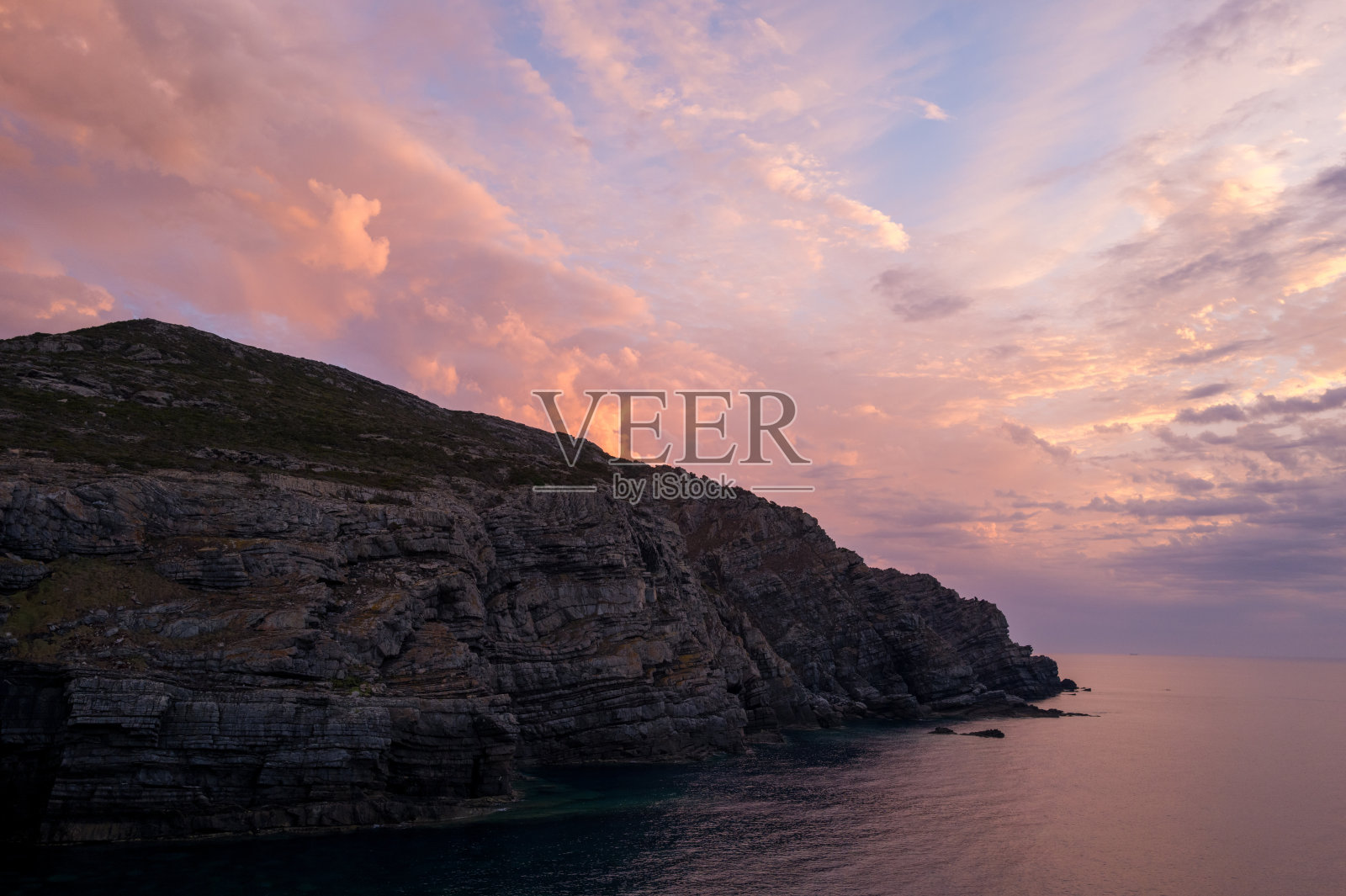 撒丁岛海岸悬崖上方的粉色日落云彩照片摄影图片