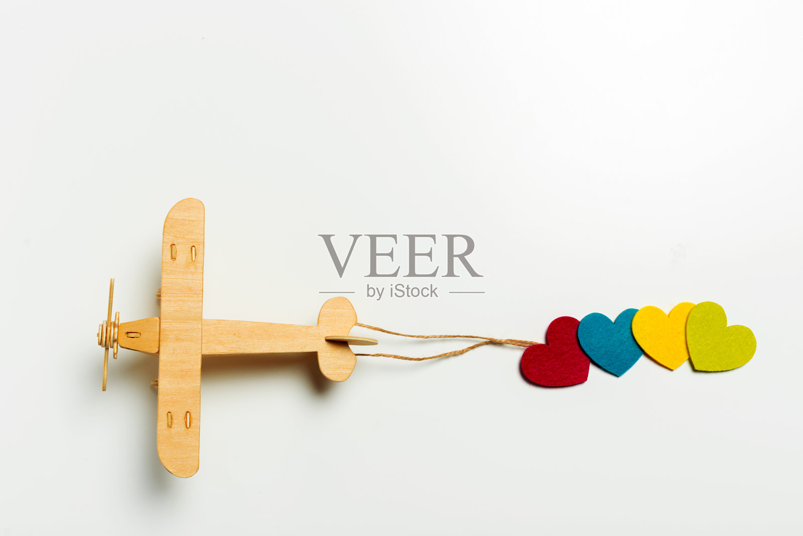 五彩缤纷的心形跟随一架木制飞机，为富有创意的玩耍时光带来欢乐和趣味照片摄影图片