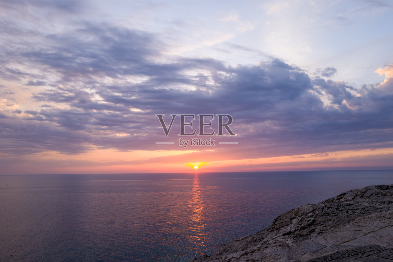 岩石海岸和宁静大海上的生动日落照片摄影图片