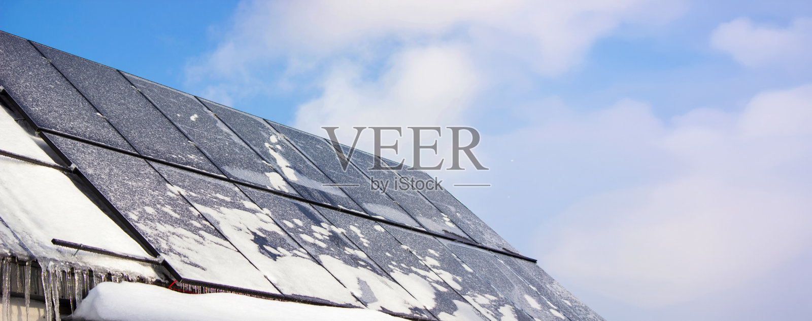 冬天，覆盖着雪和冰的太阳能电池板，霜冻中的可再生能源。照片摄影图片