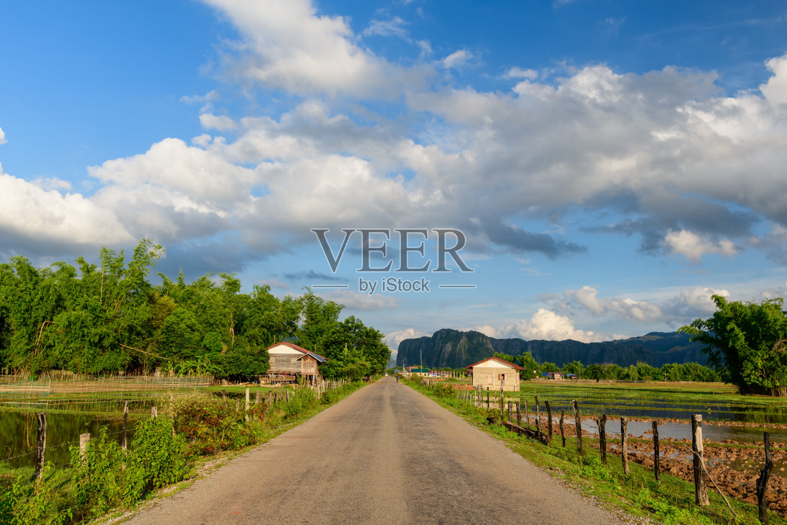 稻田与石灰岩山丘环绕的乡村道路照片摄影图片