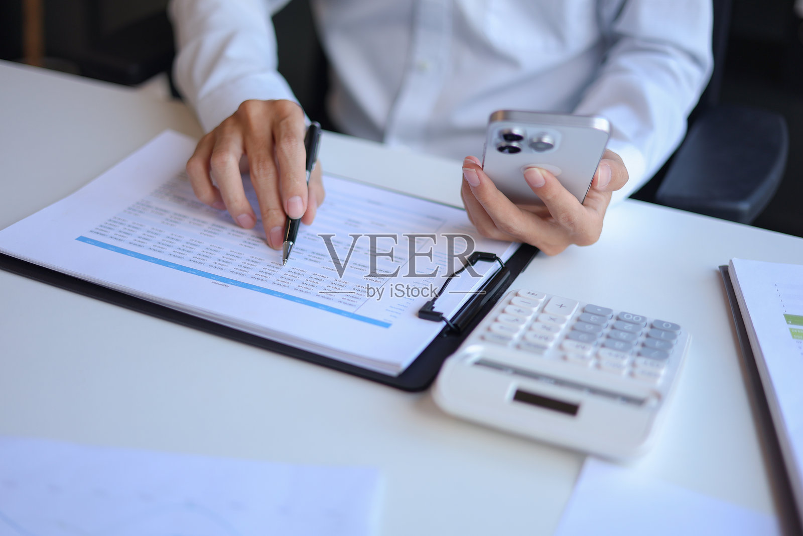 专业商人、企业家或会计师在办公桌前使用手机处理财务报告文件。照片摄影图片