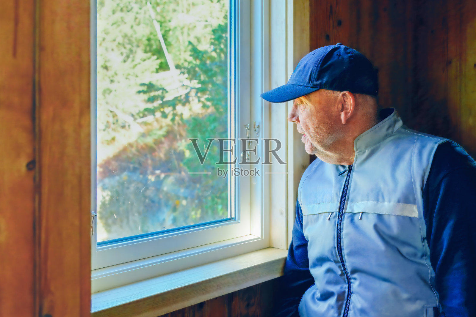 戴着蓝色帽子的中年男子若有所思地望着窗外照片摄影图片