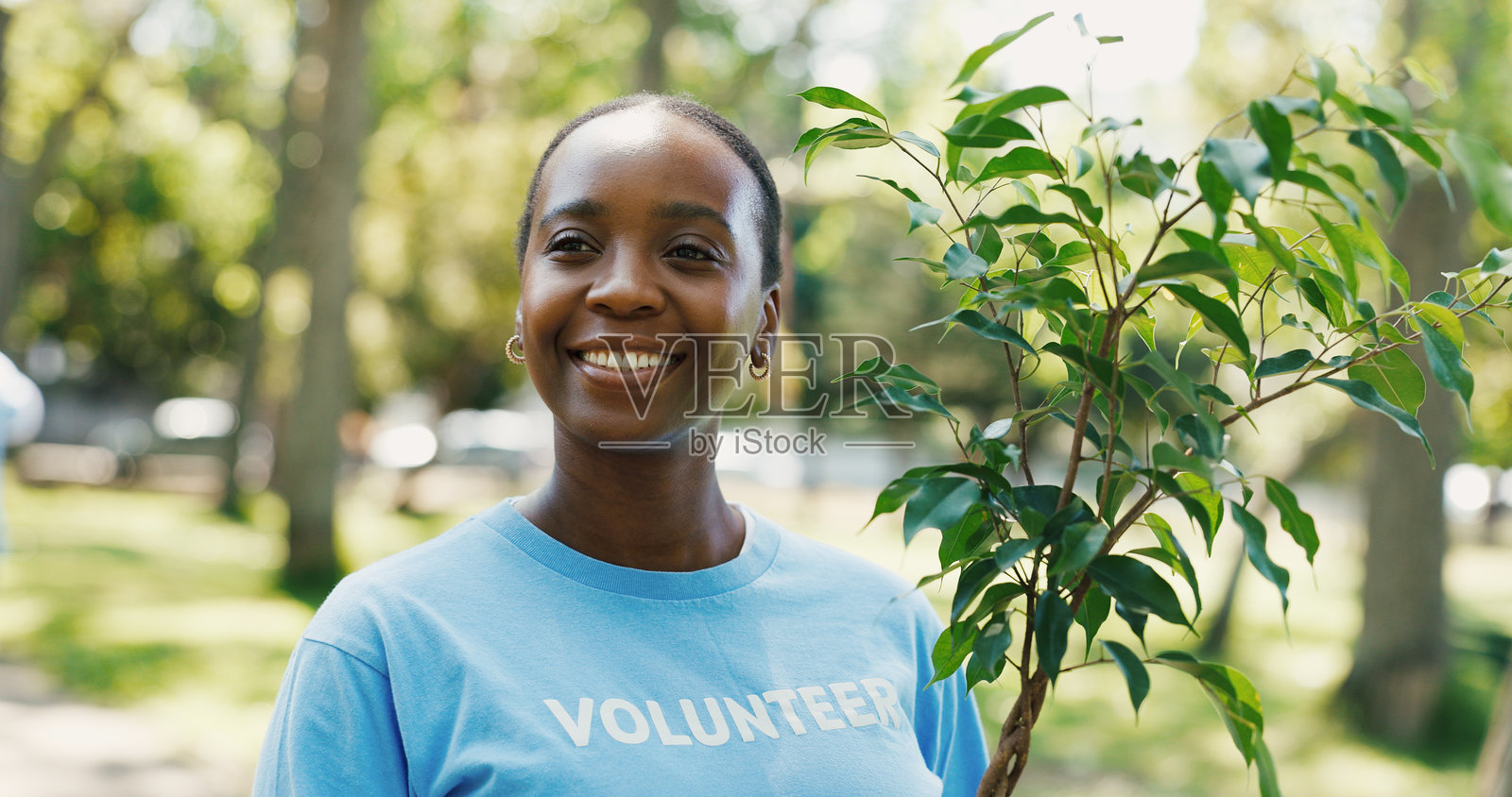 在公园里，一位黑人女性在地球日、环境和保护项目中，志愿种植并面带微笑。一个环保非政府组织，致力于可持续发展和非营利使命，与户外人士共同成长。照片摄影图片