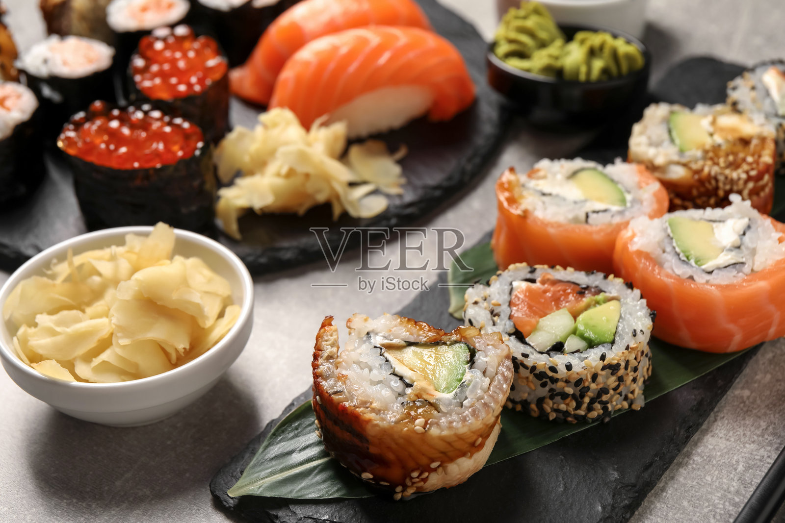 浅灰色桌子上的美味寿司卷和姜片，特写照片摄影图片