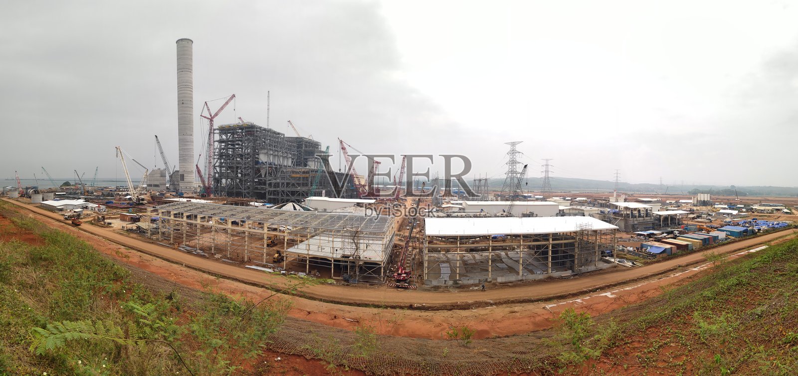 蒸汽发电厂建筑，工业建筑在繁忙的货运港口附近夜晚闪耀，天空晴朗，货船停泊在旁照片摄影图片