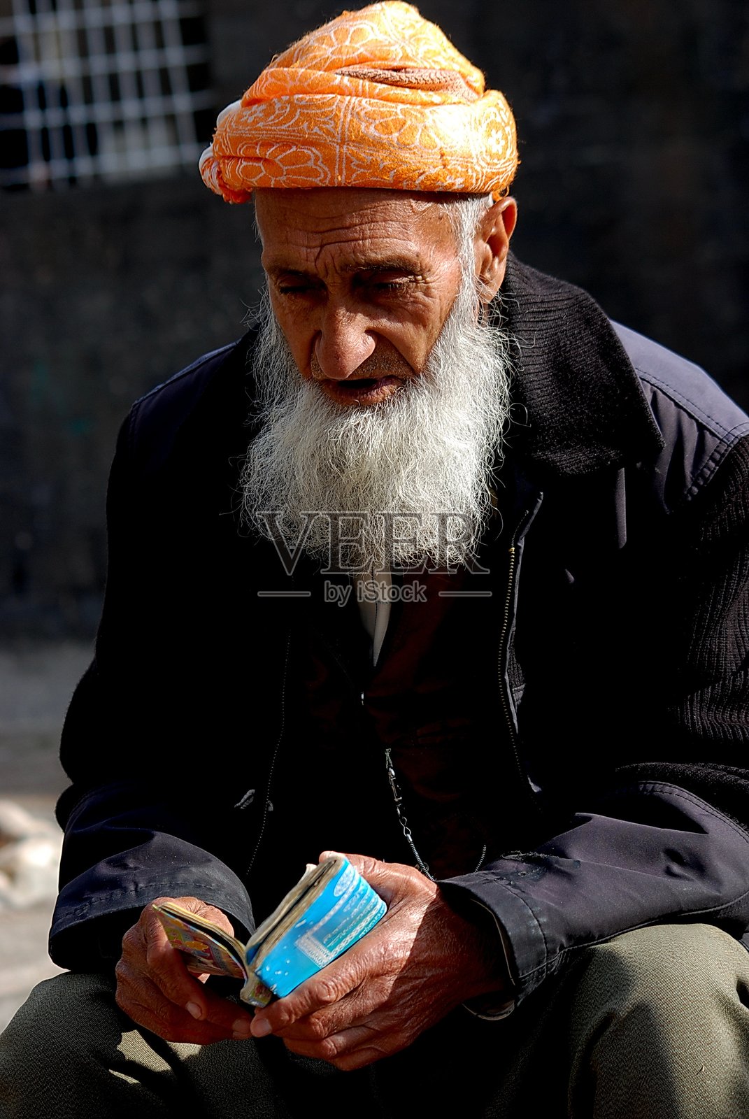 迪亚巴克尔的精神虔诚：一位白须老人明媚阳光下阅读祈祷书照片摄影图片