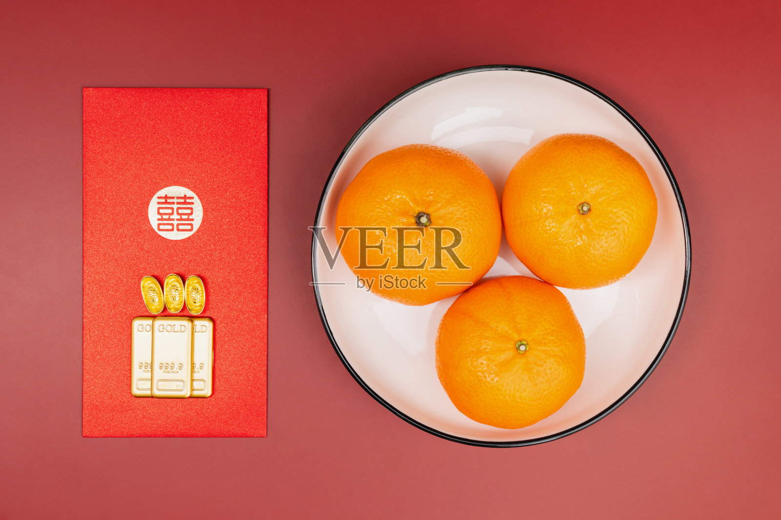 中国新年，红包、金条和橘子在红色的背景上的俯视图。照片摄影图片